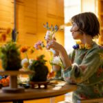 Woman sits by the table full of flowers at home